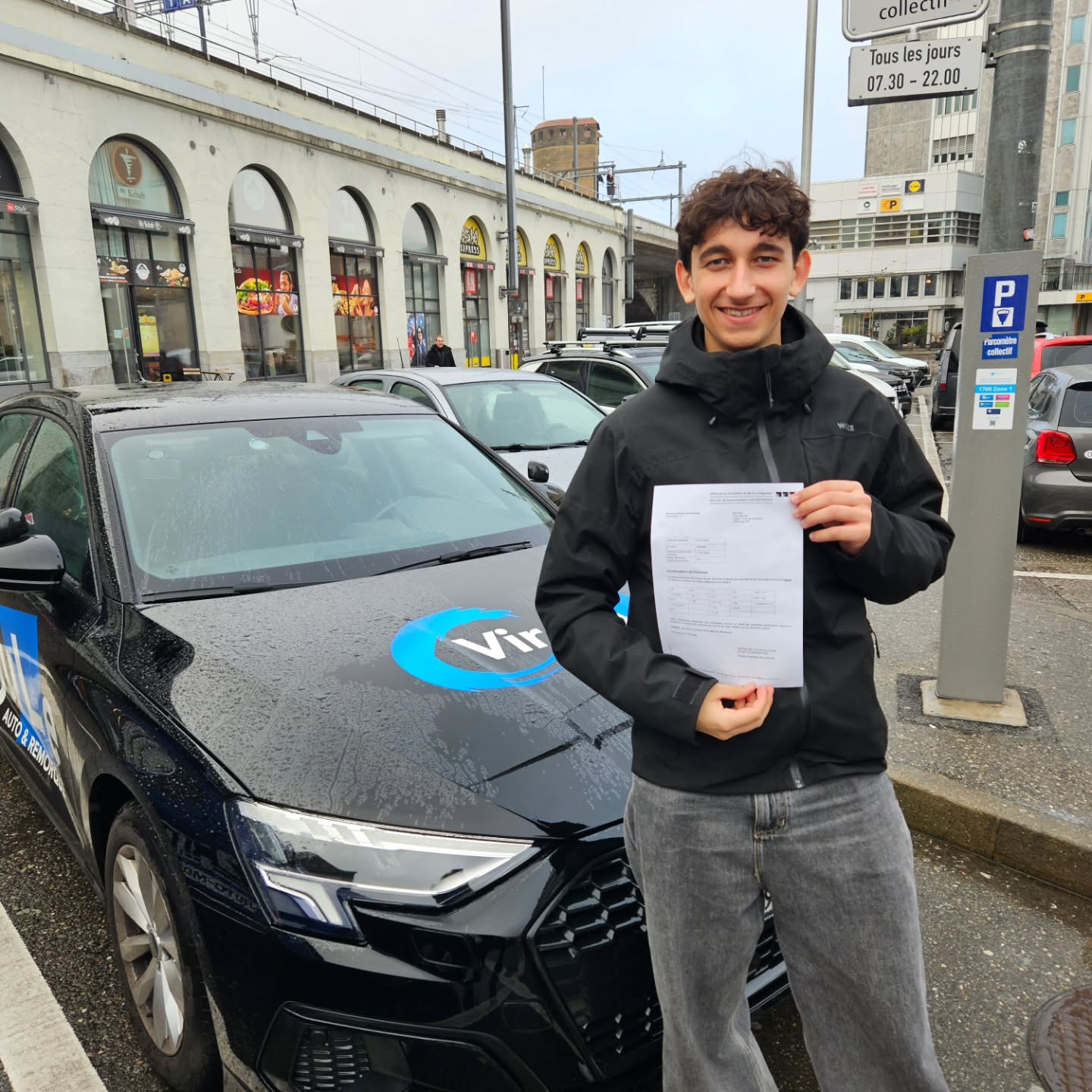 Yoan, permis réussi malgré la pluie, devant la voiture-école